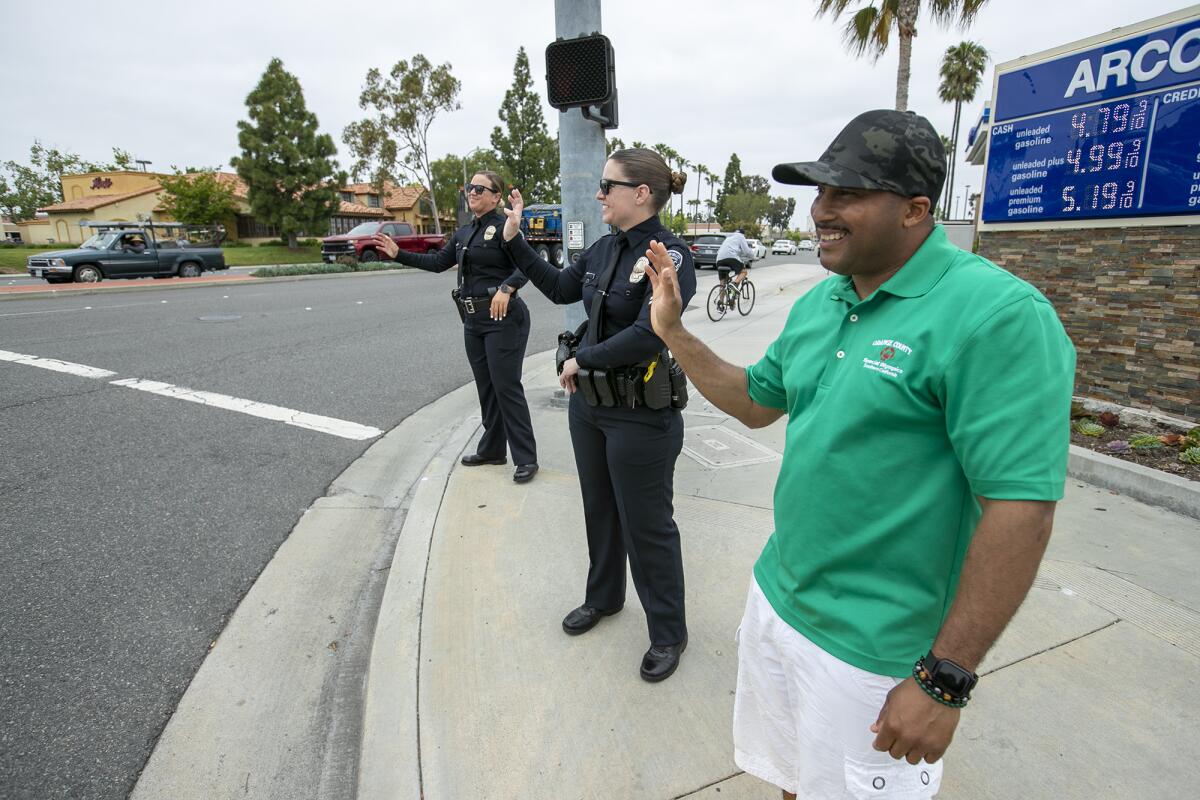  Kim Holmes, left, Cpl. Shalamar Nielsen, center and Special Olympic athlete Chris Dorsey wave to motorists Thursday.