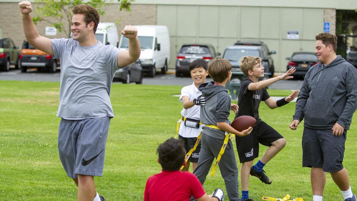Newport Beach residents Kevin Marheine, left, and his twin brother, Nick, run drills with the Bengals, the flag football team they coach.