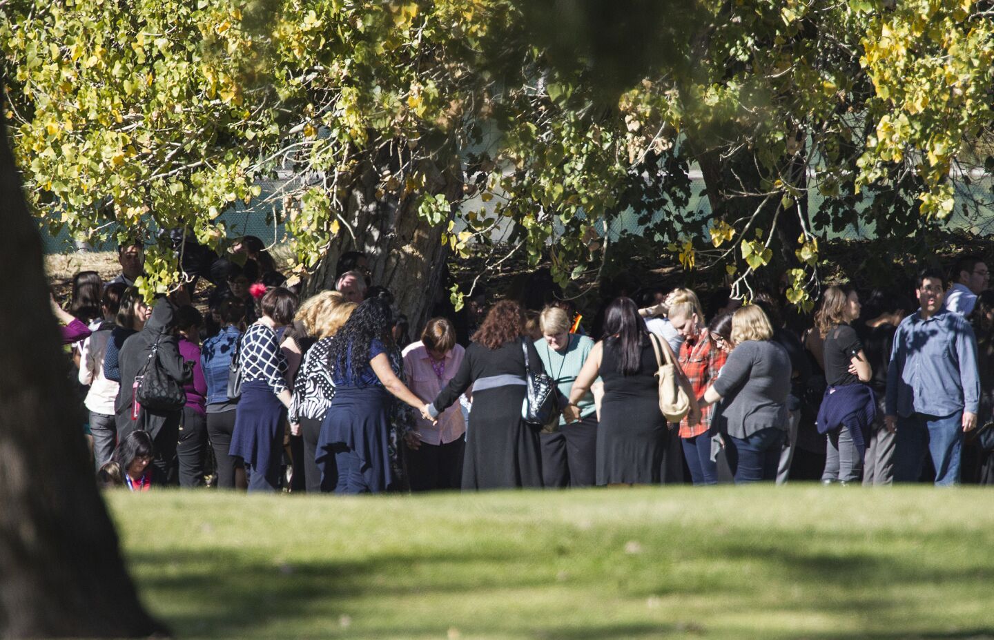 Evacuated workers join in a circle to pray on the San Bernardino Golf Course across the street from where a shooting occurred at the Inland Regional Center.