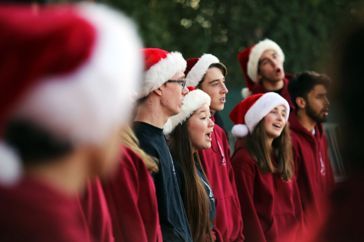 A group of high school singers performs wearing Santa hats. 