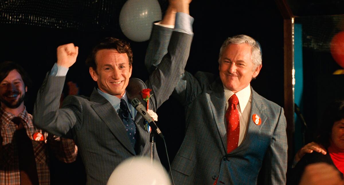 One man holds another man's up in the air in celebration at a political rally in "Milk."