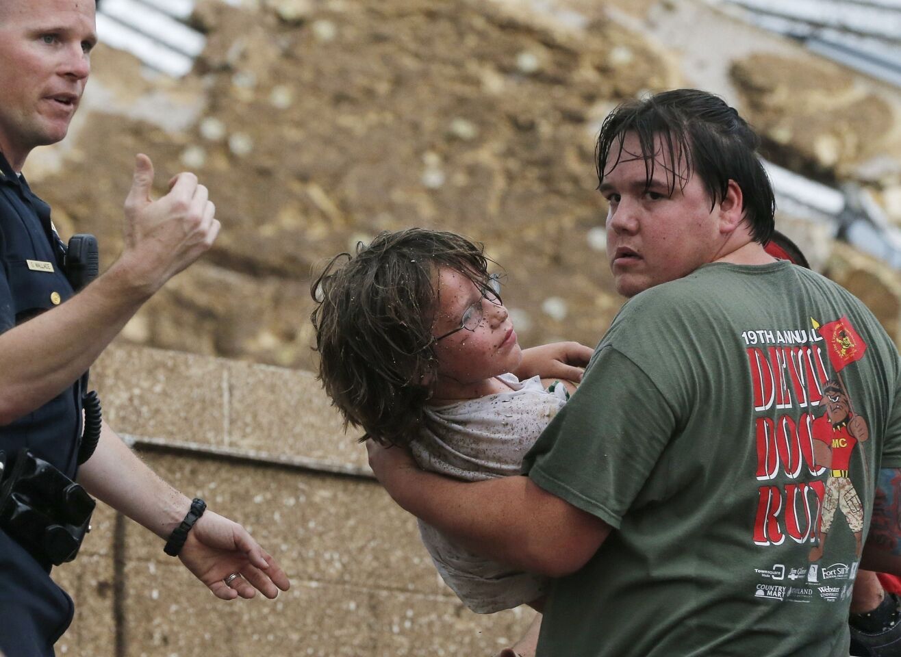 A child is carried from the rubble of the Plaza Towers Elementary School following a tornado in Moore, Okla.