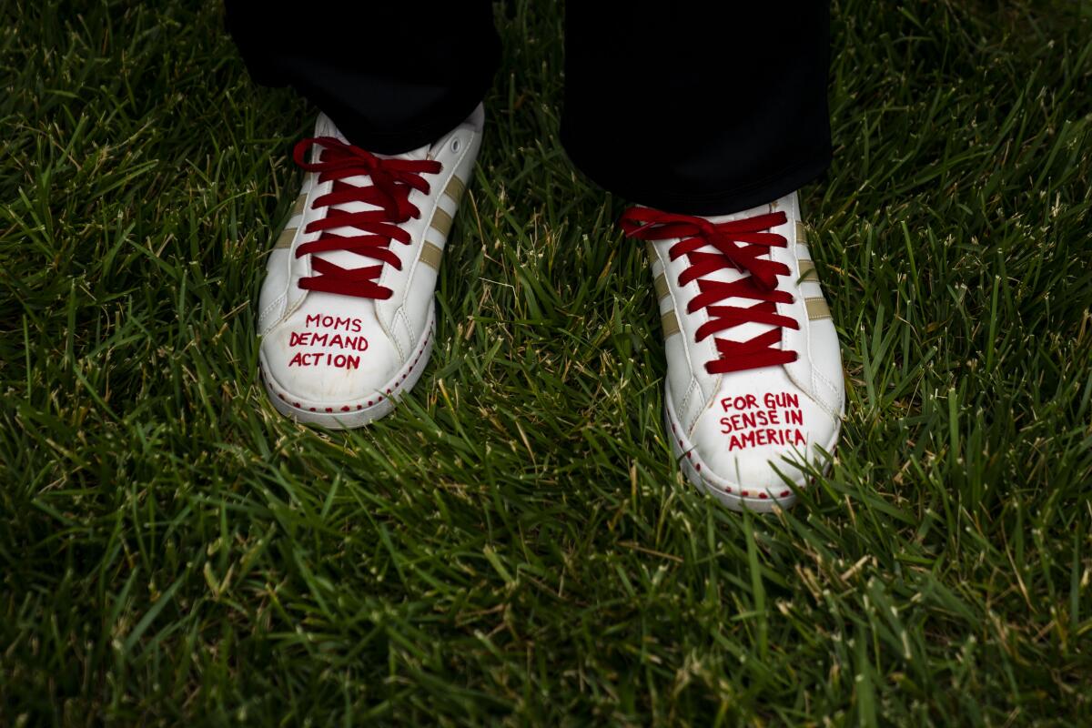 A woman wears sneakers with the words "Moms demand action for gun sense in America" written on the toes