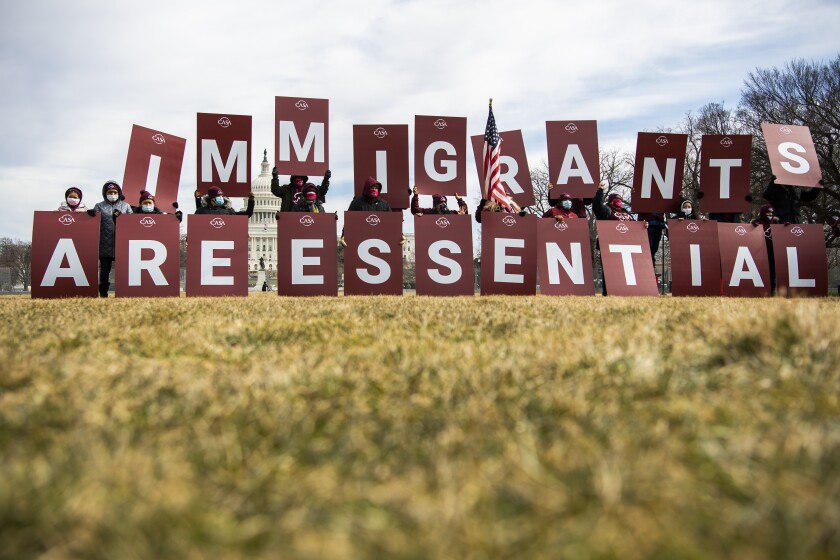 A group of people hold letters spelling, "Immigrants are essential"