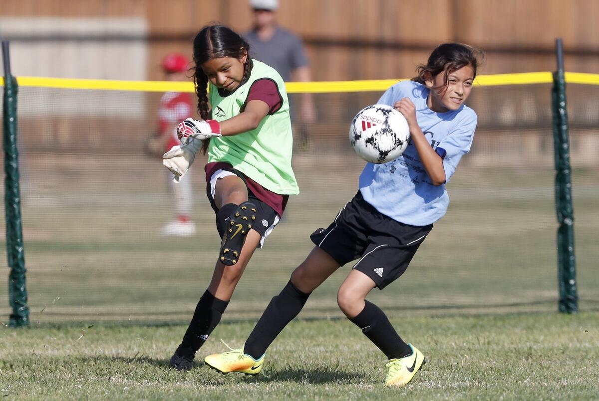 Sonora Elementary goalkeeper Michelle Villalva, left, clears the ball against California's Sophia Zarate in a girls’ third- and fourth-grade Bronze Division pool-play match at the Daily Pilot Cup on Thursday at Costa Mesa High.