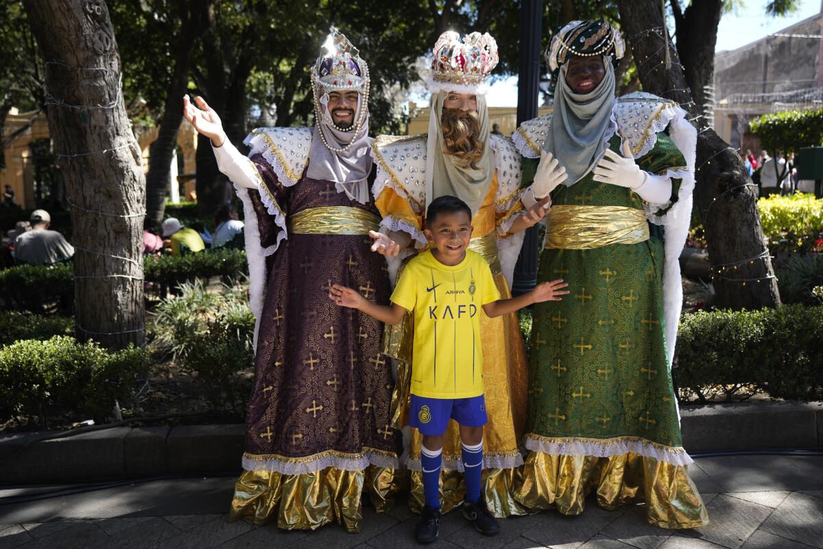Un niño posa para una foto con personas disfrazadas de los Reyes Magos