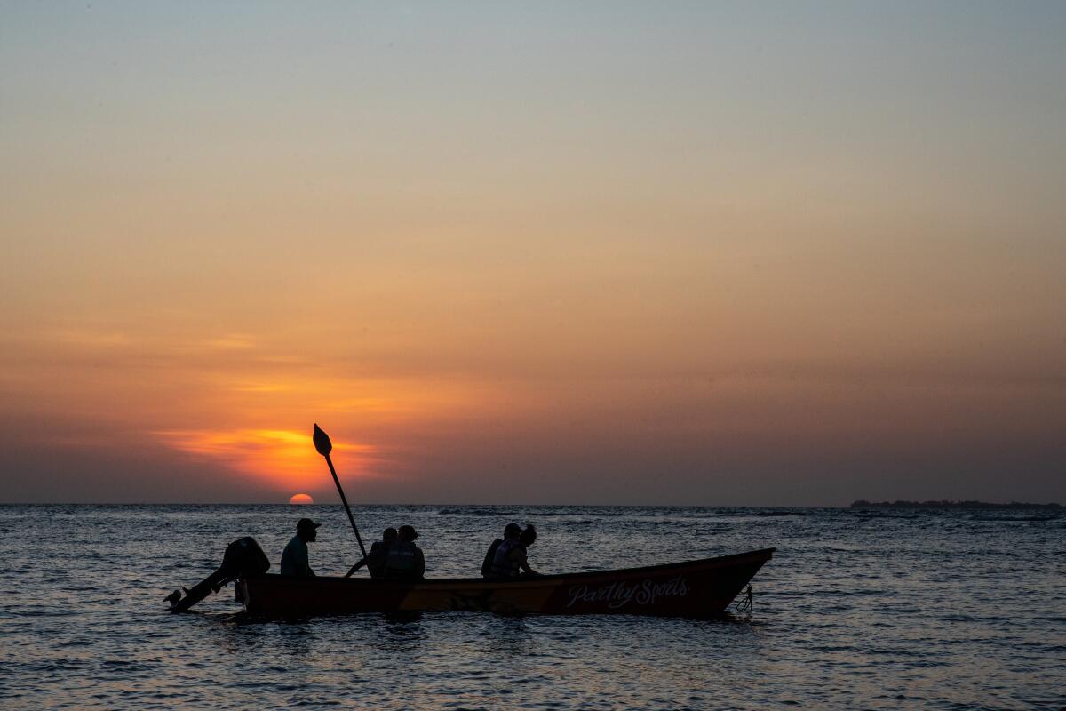 A sunset bird-watching tour on the Caribbean Sea near Rincón del Mar, Colombia, with passengers in silhouette.