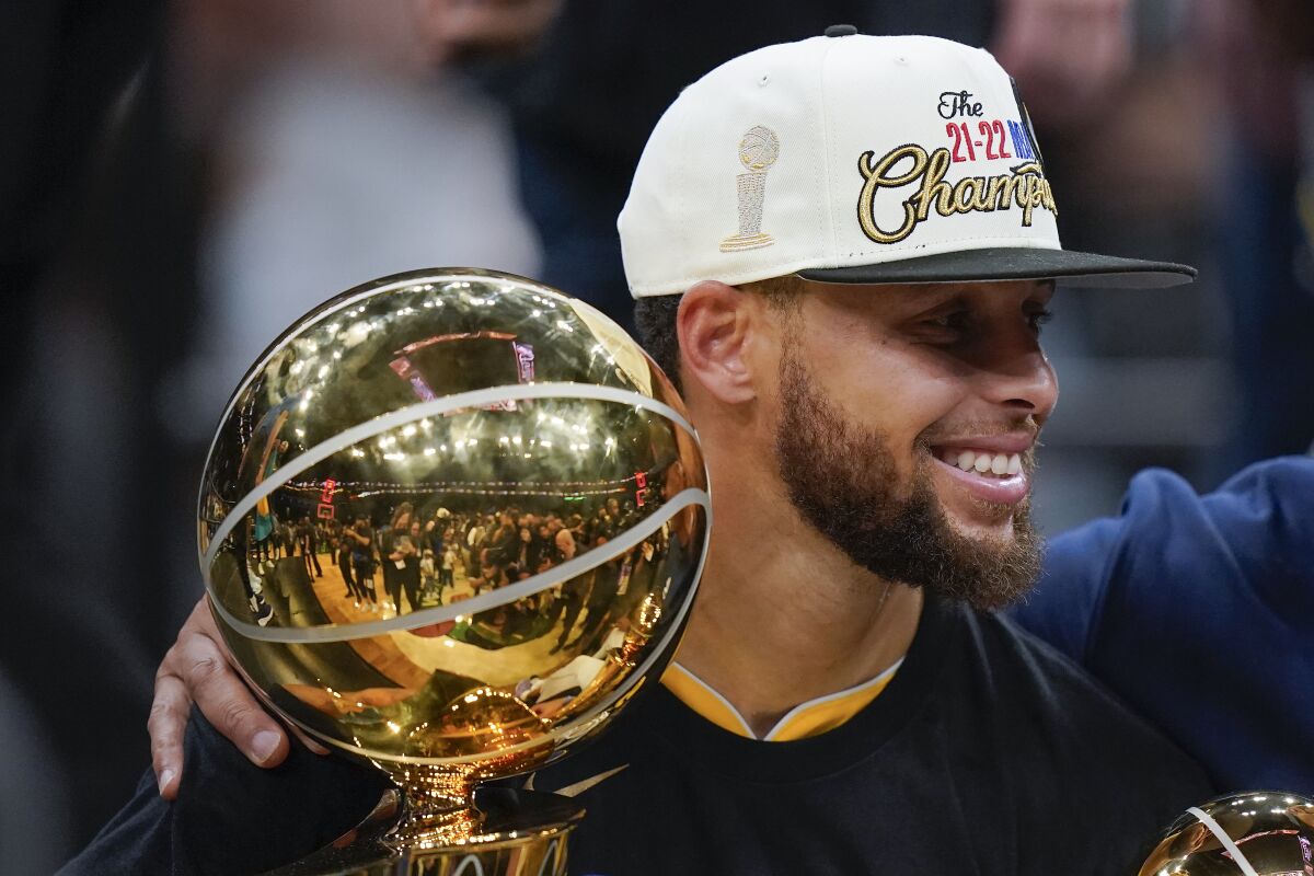 Golden State Warriors guard Stephen Curry, center, celebrates with teammates as he holds the Larry O'Brien Trophy after the Warriors beat the Boston Celtics in Game 6 to win basketball's NBA Finals, Thursday, June 16, 2022, in Boston. (AP Photo/Steven Senne)