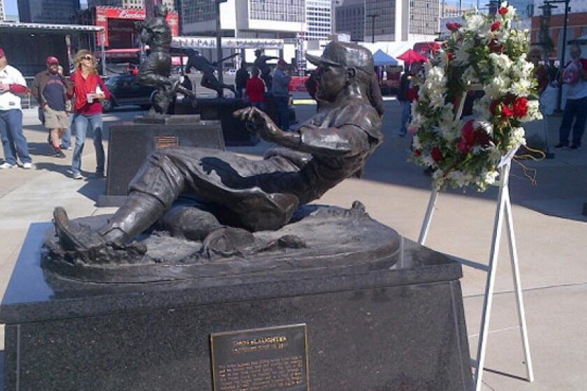A wreath stands next to a statue honoring Cardinals great Enos Slaughter outside Busch Stadium in St. Louis on Saturday.