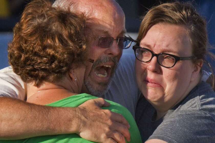 Tom Sullivan, center, embraces family members after his son, Alex, who celebrated his 27th birthday by going to see "The Dark Knight Rises," was among those killed in the Colorado movie theater shooting.