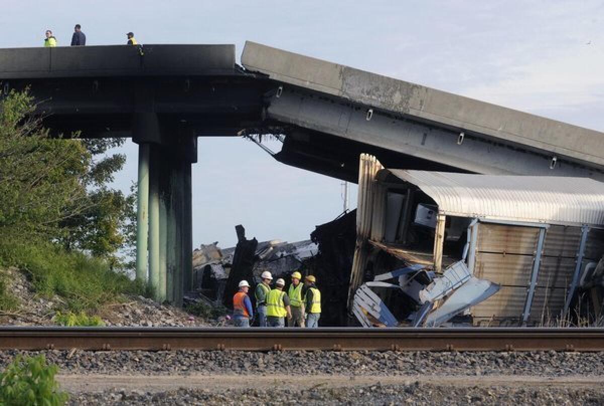Emergency personnel investigate the Route M overpass at Rockview, Mo., about 10 miles south of Cape Girardeau, Mo., after it collapsed onto the railroad tracks. The National Transportation Safety Board has launched an investigation into the cause of a cargo train collision.