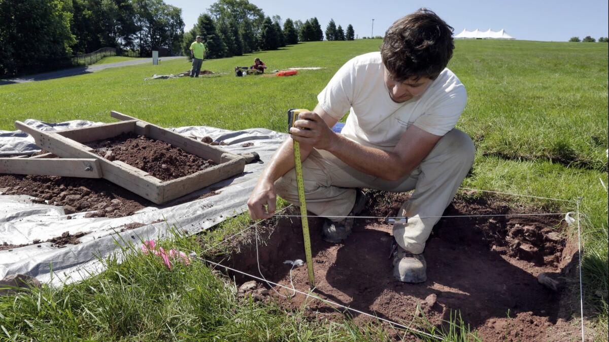 Paul Brown, of the Public Archaeology Facility at Binghamton University, measures a dig at the site of the original Woodstock Music and Art Fair in Bethel, N.Y.