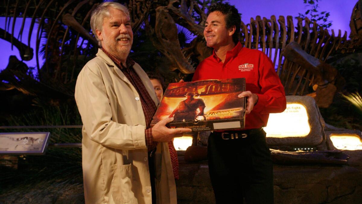 Papa John's founder John Schnatter, right, hands over a free pizza to Dr. Rick Jones, Indiana's official archeologist, as part of a company promotion. Papa John’s is gearing up for a fight with Schnatter, who resigned as chairman but remains the company's largest shareholder.
