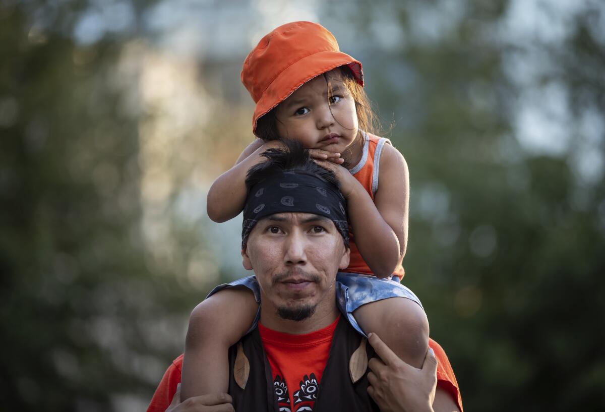 Cowichan Tribe member Benny George holds his child on his shoulders 