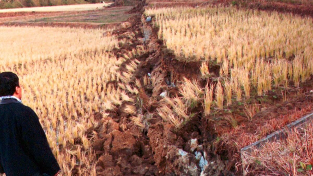 Researchers inspect a fissure running through fields for five miles following an earthquake near Kobe, Japan, in 1995.. (Tokyo Shimbun/ Associated Press)