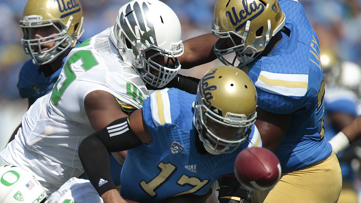 UCLA quarterback Brett Hundley fumbles after being hit by Oregon defensive lineman Tui Talia, left, during the first quarter of Saturday's loss to the Ducks.