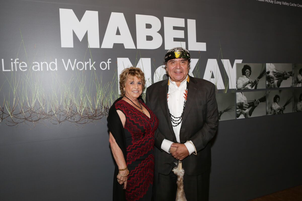 Marshall McKay and Sharon Rogers McKay stand before a wall text that reads "The Life and Work of Mabel McKay"