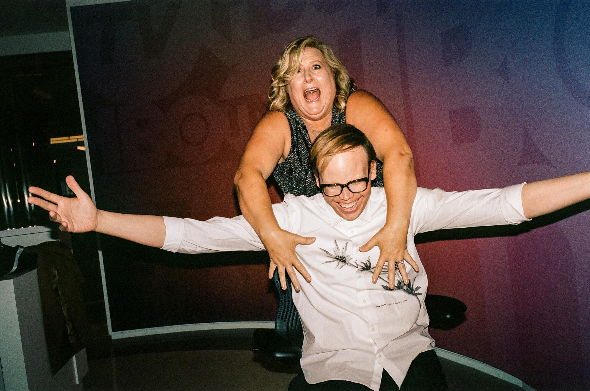 A woman pushes a man in a chair with wheels