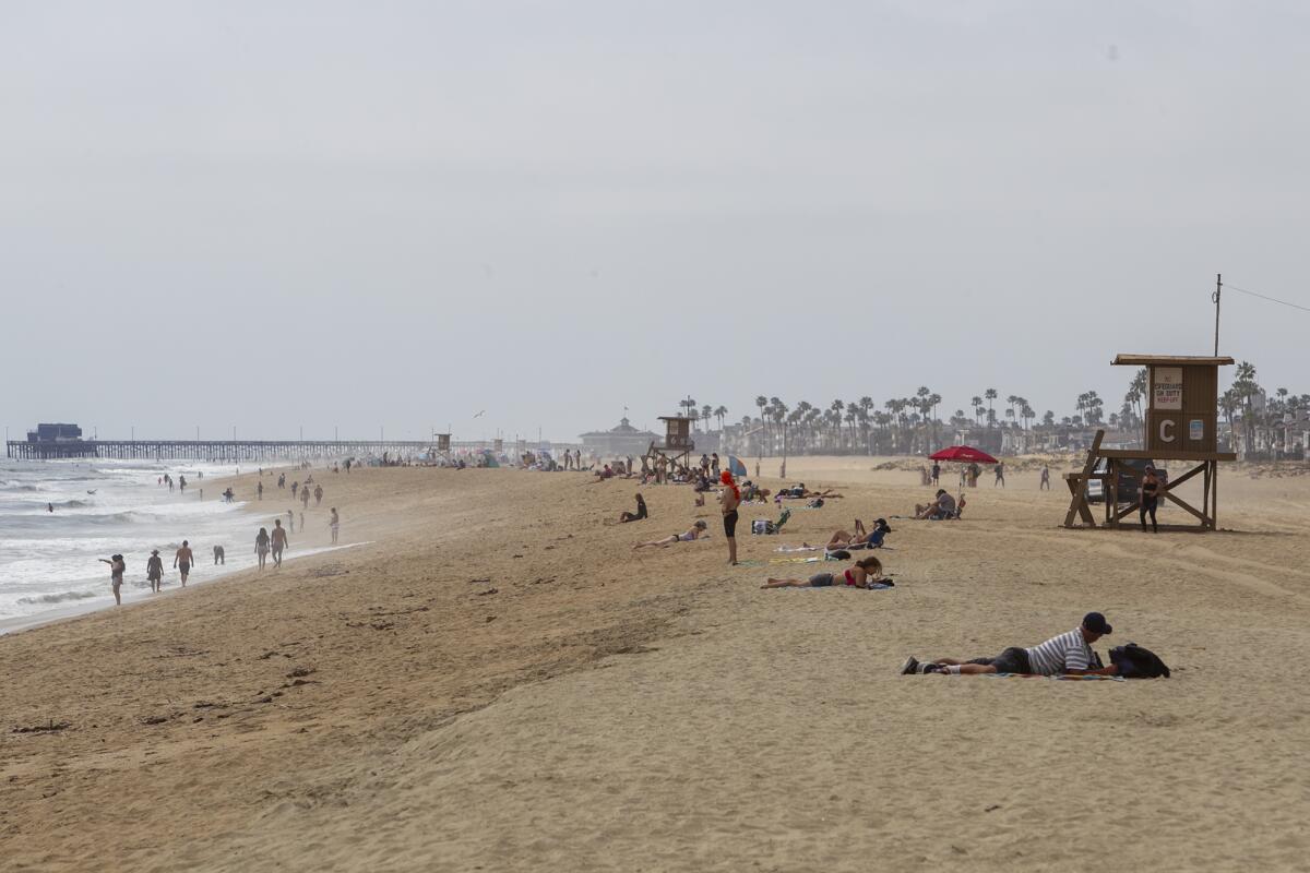 People gather in Newport Beach near the Balboa Pier on Thursday, the day Gov. Gavin Newsom announced a hard closure of Orange County beaches.