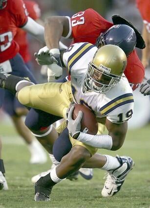 UCLA's Marcedes Lewis is tackled by Arizona's Ronnie Palmer during the first half.