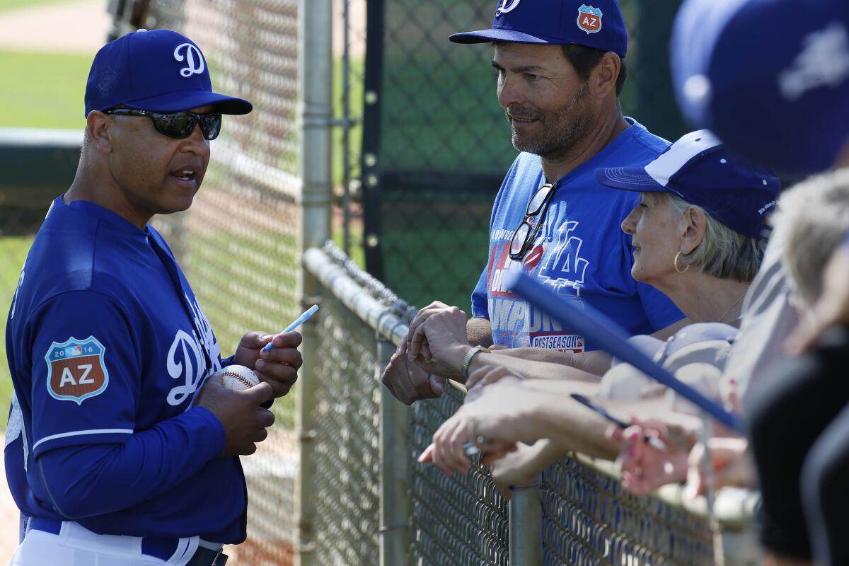 Manager Dave Roberts sign autographs for fans at the end of a Dodgers spring training session at Camelback Ranch on Feb. 24.
