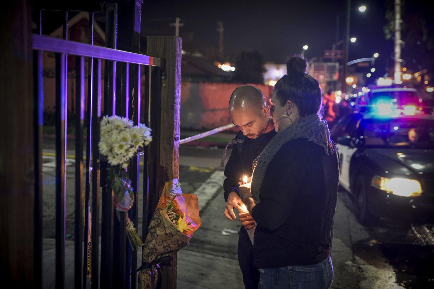 Dino Graniello, left, and Jessie Xenakis light candles near the scene of a warehouse fire in Oakland that killed at least two dozen partygoers.
