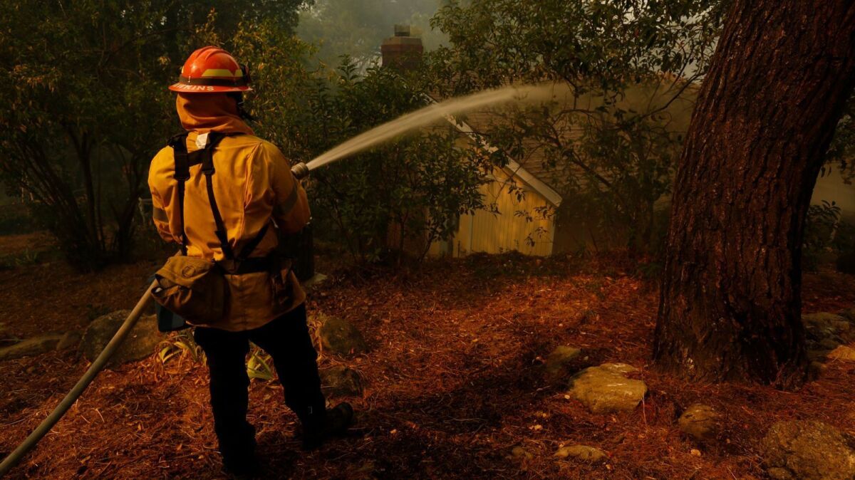 Los Angeles City firefighter Robert Hawkins hoses down a home to protect it from the La Tuna fire in Sunland.