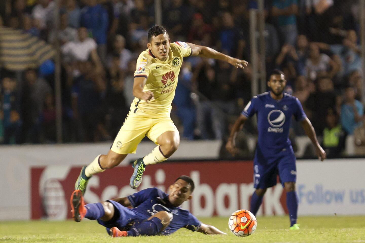 Andrés Andrade (c) del América, escapa ante la presión de Irvin Reyna (abajo), del Motagua, en juego de la Liga de Campeones de la Concacaf, en el estadio Nacional de Tegucigalpa, Honduras.