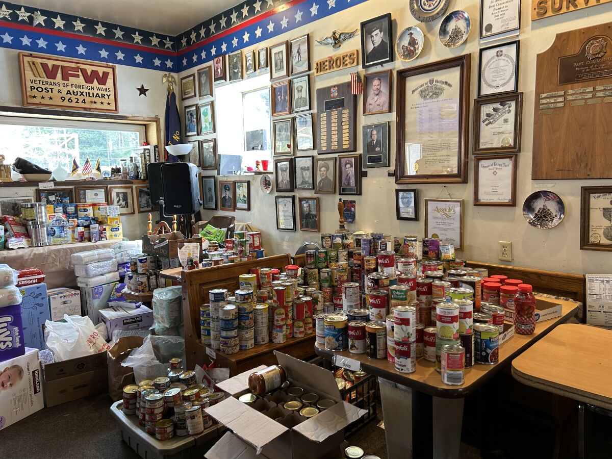 Cans are on tables and boxes on the ground inside a room.