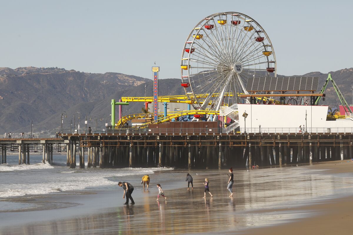 Image of people on the beach by Santa Monica Pier