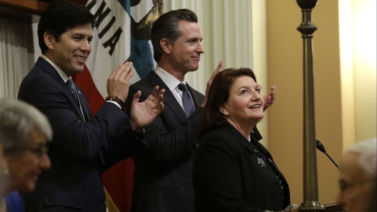 State Sen. Toni Atkins (D-San Diego) smiles up at the Senate gallery after being sworn in as the new Senate president pro tem Wednesday. She replaces former Sen. Kevin de Leon (D-Los Angeles), left. In the center is Lt. Gov. Gavin Newsom.