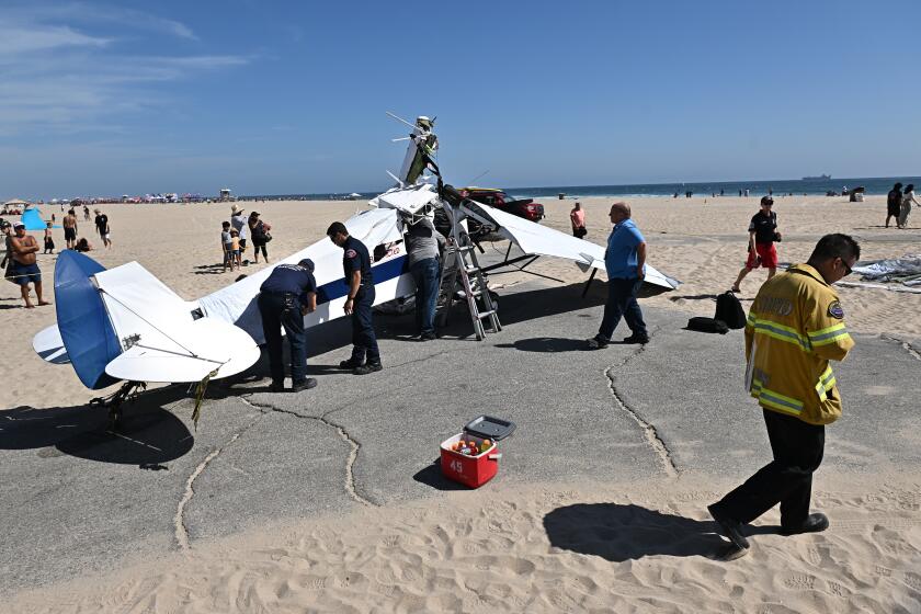Huntington Beach, California July 22, 2022-Officials inspect the damage from a plane that crashed into the water in Huntington Beach Friday. (Wally Skalij/Los Angeles Times)