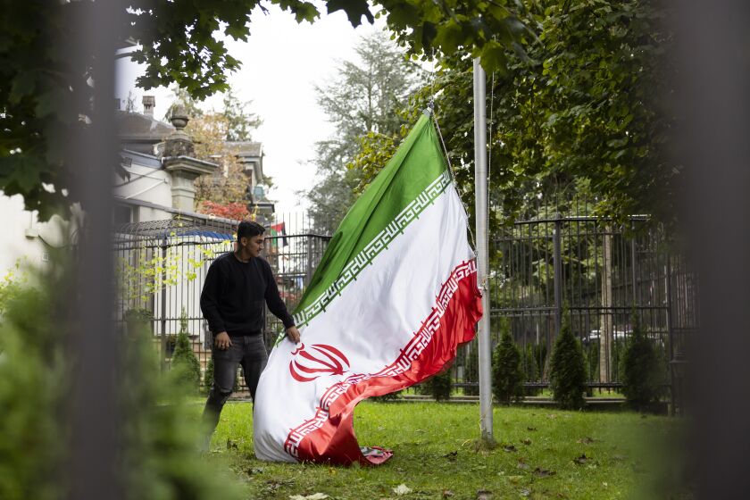 Un manifestante arría la bandera iraní en los terrenos de la embajada iraní, durante protestas globales contra el régimen de Irán, en la embajada iraní de Berna, Suiza, el sábado 1 de octubre de 2022. (Peter Klaunzer/Keystone via AP)