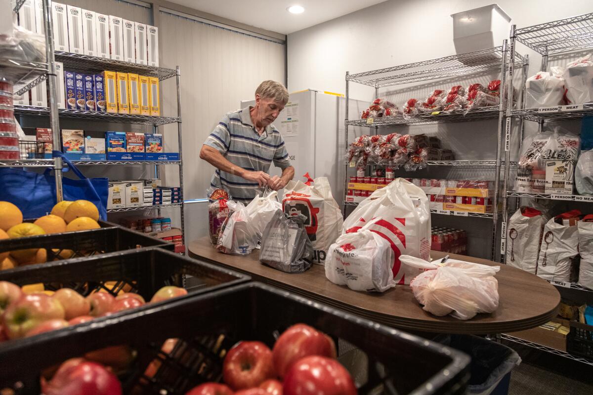 a man in a striped shirt fills groceries in a storage room