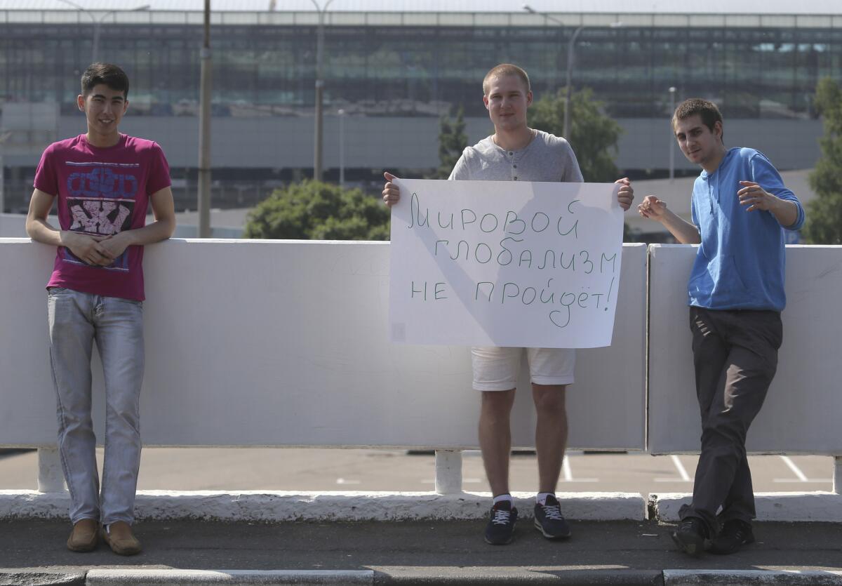 A supporter of Edward Snowden holds a poster outside Sheremetyevo airport in Moscow on Friday. Snowden is believed to be staying at the airport's transit zone. The poster reads: "World Globalism will not Rule!!"