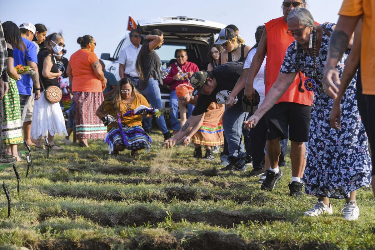 FILE - In this July 17, 2021, file photo ,relatives and tribal members throw dirt into the graves of the Rosebud Sioux children, at a funeral 142 years after their deaths, at the Rosebud Sioux Tribe Veterans Cemetery in White River, S.D. The American Bar Association’s policymaking body voted Monday, Aug. 9,2021, in favor of a resolution supporting the U.S. Interior Department as it works to uncover the troubled legacy of federal boarding schools that sought to assimilate Indigenous youth into white society. (Erin Bormett/The Argus Leader via AP, File)