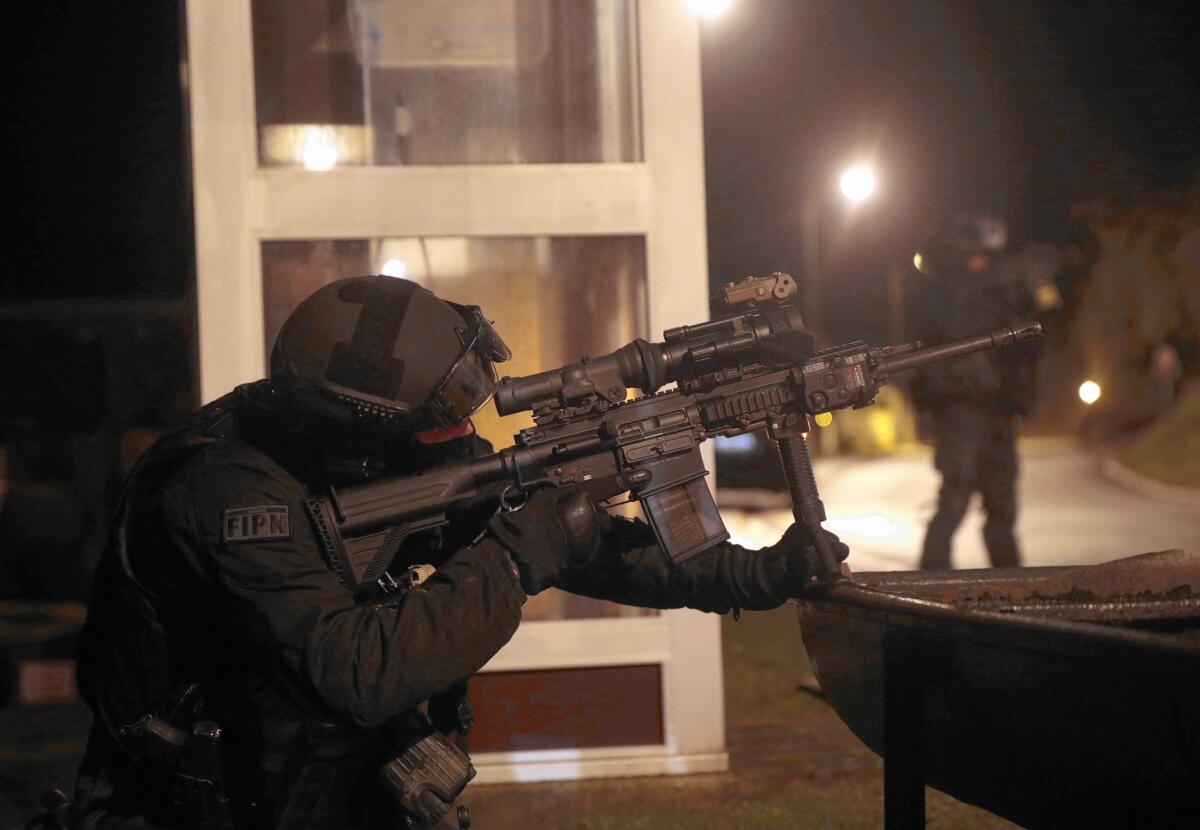 A member of the French police intervention force aids in a search in Fleury the day after the Charlie Hebdo attack.