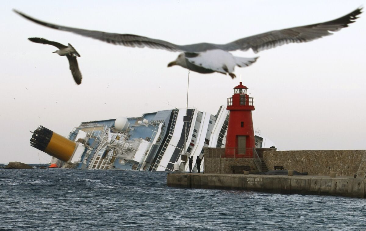FILE— Seagulls fly in front of the grounded cruise ship Costa Concordia off the Tuscan island of Isola del Giglio, Italy, Monday, Jan. 30, 2012. Italy on Thursday, Jan. 13, 2022, is marking the 10th anniversary of the Concordia disaster with a daylong commemoration, honoring the 32 people who died but also the extraordinary response by the residents of Giglio who took in the 4,200 passengers and crew from the ship on that rainy Friday night and then lived with the Concordia carcass for another two years before it was hauled away for scrap. (AP Photo/Pier Paolo Cito)