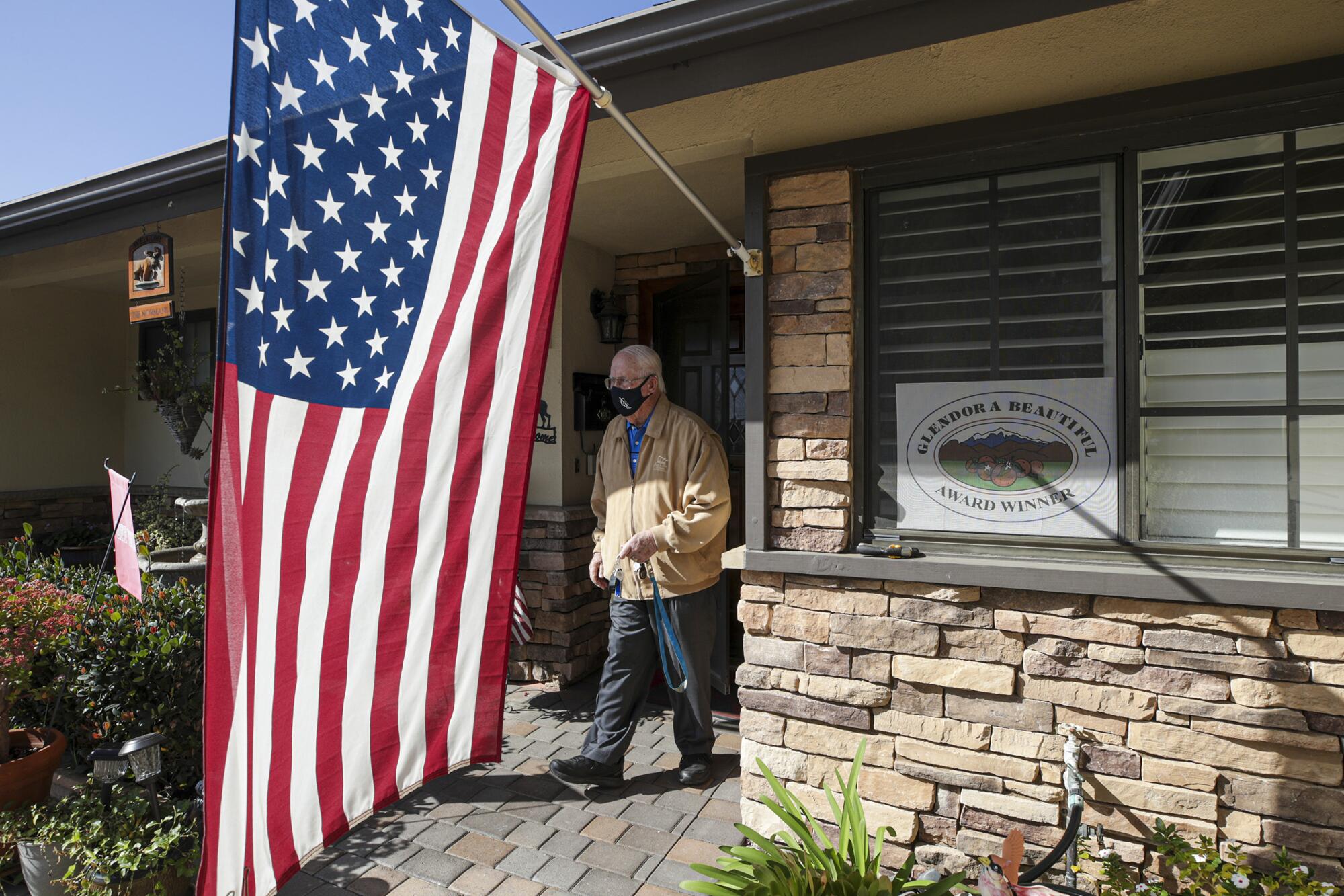 A man walks out of his front door under a U.S. flag