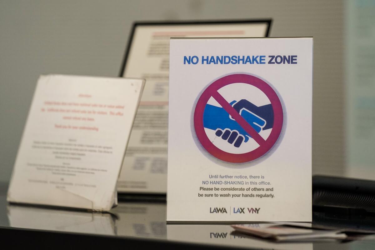 A sign warning travelers not to shake hands is seen at an information desk at the Tom Bradley International Terminal at Los Angeles International Airport.