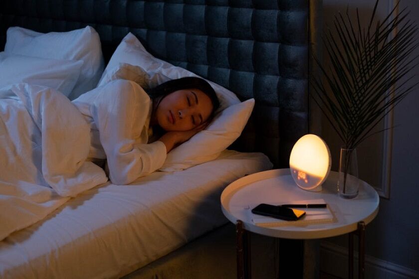 Sleeping person waking up with a light therapy alarm clock