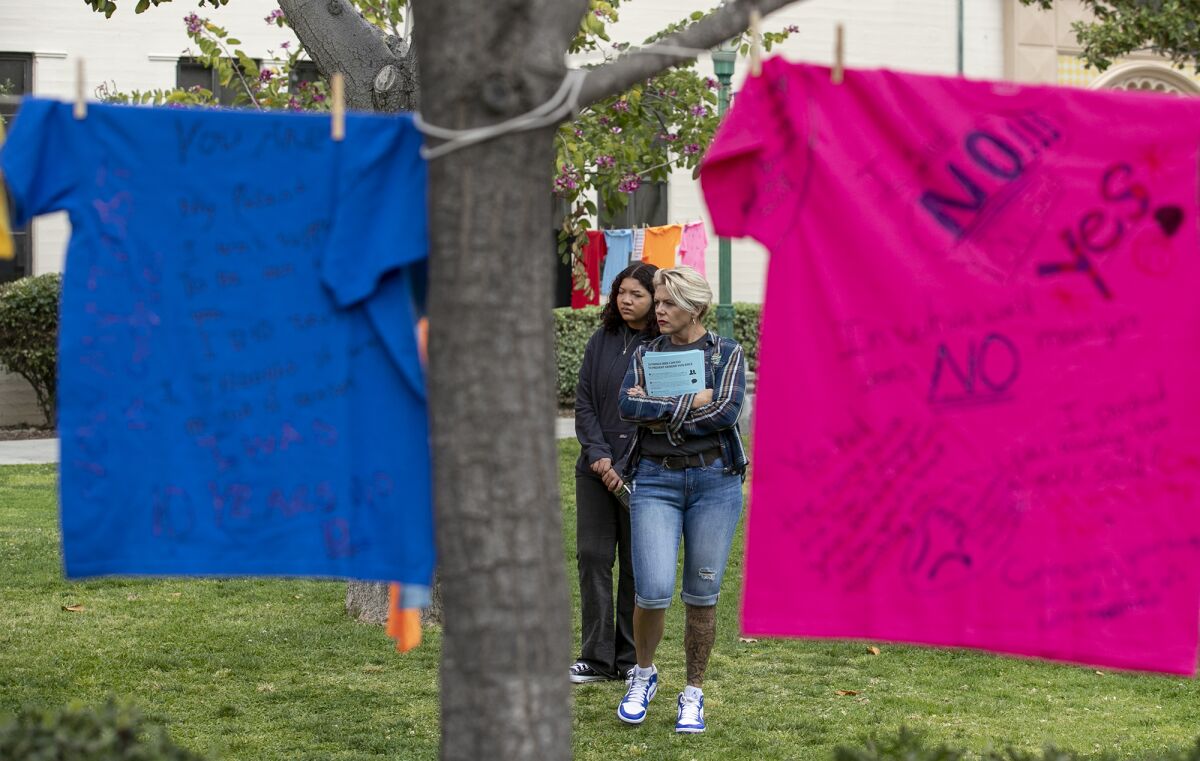 Jennifer Tetiva and her daughter, Analecia, read T-shirts at Fullerton College on April 18.