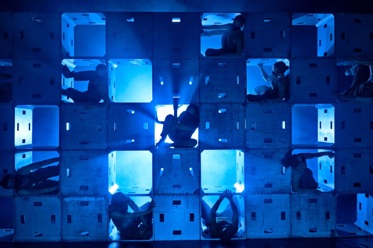 A still from "This Is Me: Letters from the Front Lines" shows dancers wedged into boxes stacked on a stage.