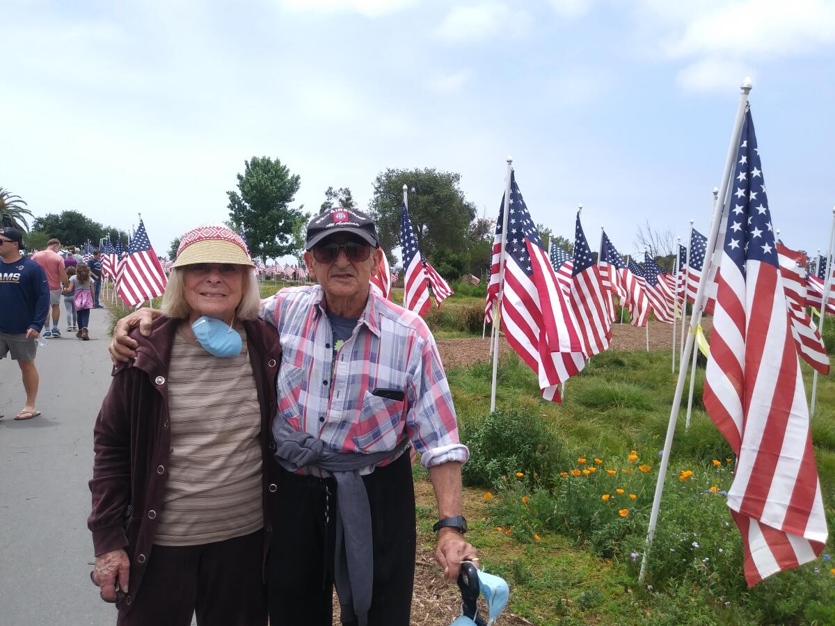 Carole and Lawrence Freedman stand among the flags at Castaways Park in Newport Beach in 2021.