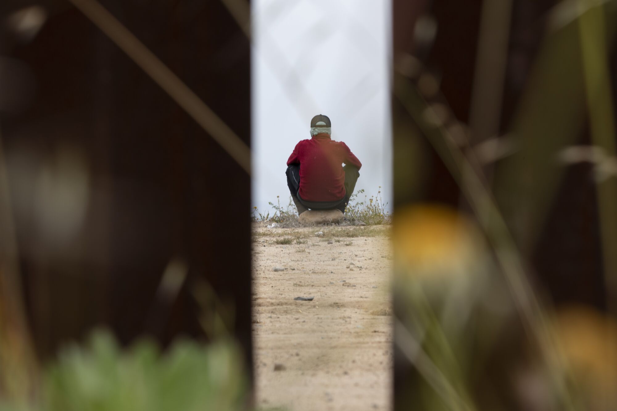 A man looks over to the United States as he waits between the border walls the day after Title 42 ended.