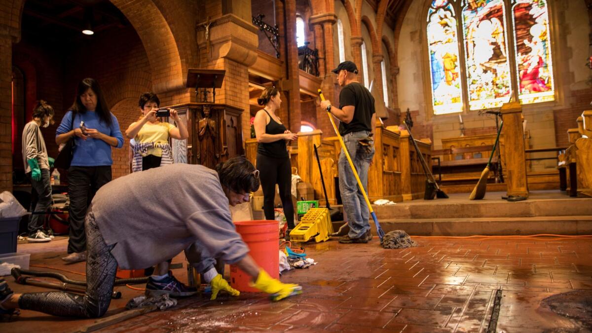 Volunteers clean up damage caused by a small fire inside of Church of the Angels in Pasadena.