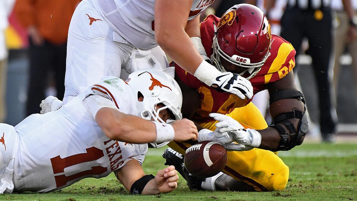 Texas quarterback Sam Ehlinger fumbles the ball in front of USC defensive lineman Rasheem Green during the first quarter of a game at the Coliseum. The Trojans recovered the ball.