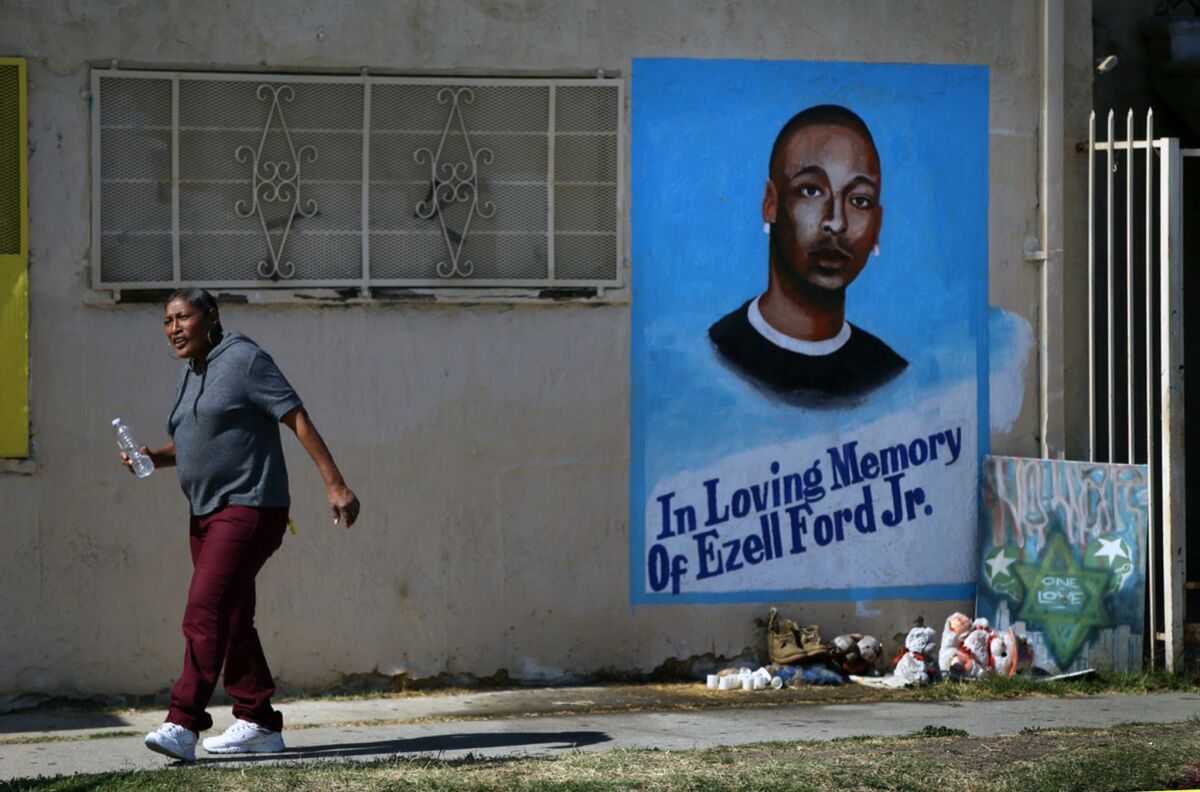 A supporter walks past an Ezell Ford remembrance painted on a wall at 65th Street and Broadway in Los Angeles.