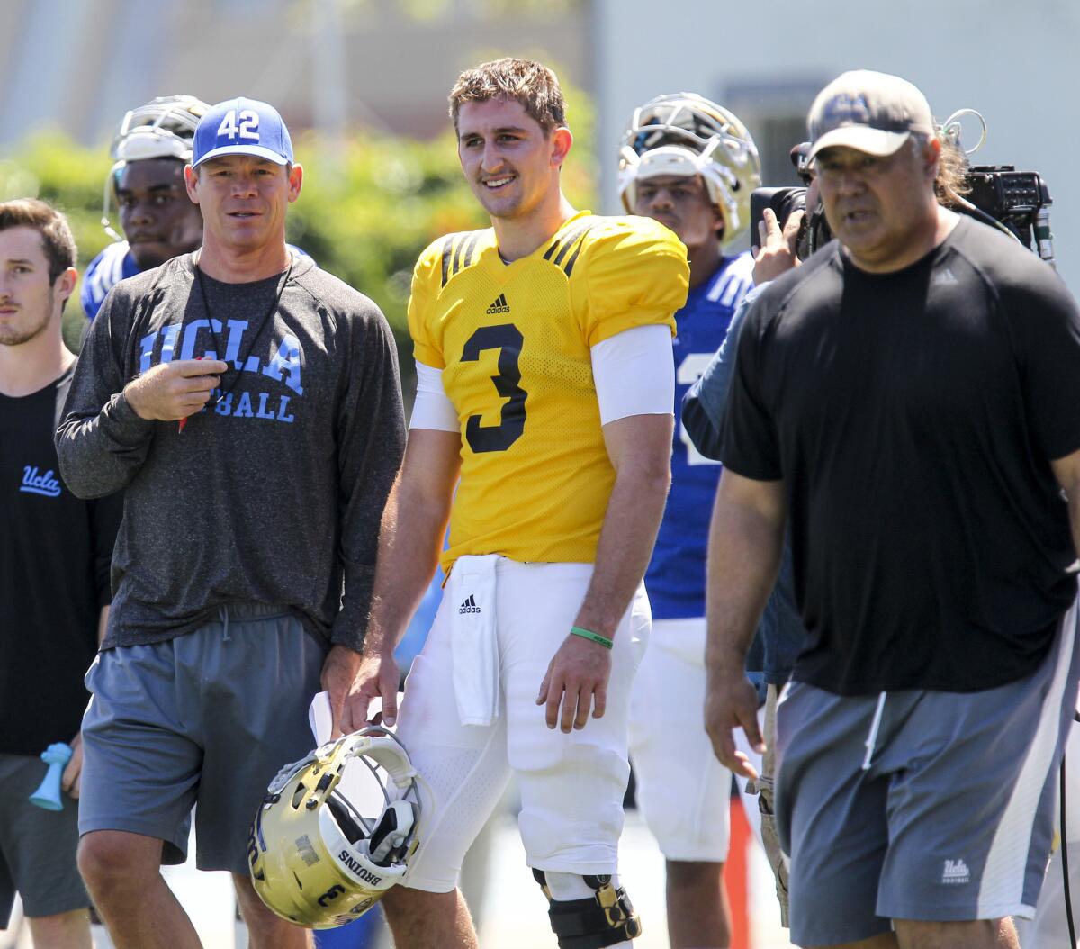UCLA offensive coordinator Kennedy Polamalu, right, is not saying whether quarterback Josh Rosen, with Coach Jim Mora to his right, participated in practice after being injured against Arizona State.