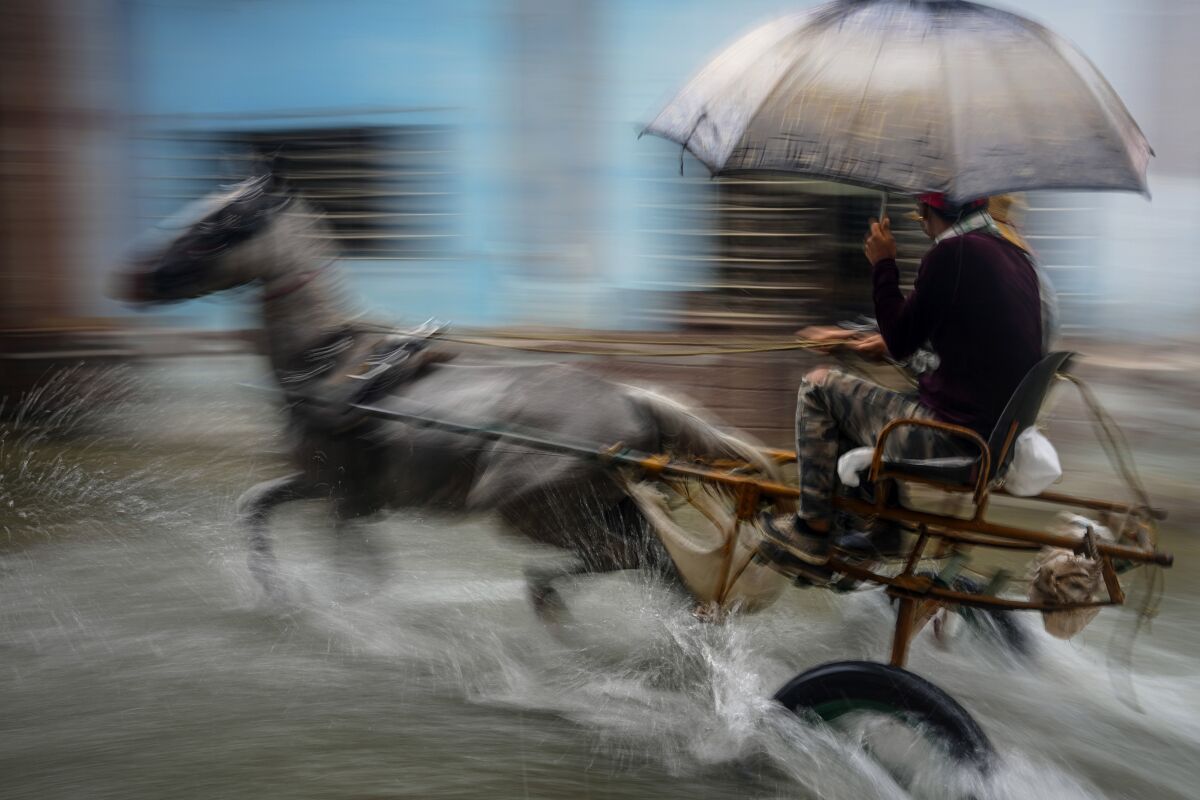 A horse pulls a buggy with passengers through a street flooded by heavy rains, in Havana, Cuba, Friday, June 3, 2022. Heavy rains have drenched Cuba with almost non-stop rain for the last 24 hours as tropical storm watches were posted Thursday for Florida, Cuba and the Bahamas as the system that battered Mexico moves to the east. (AP Photo/Ramon Espinosa)